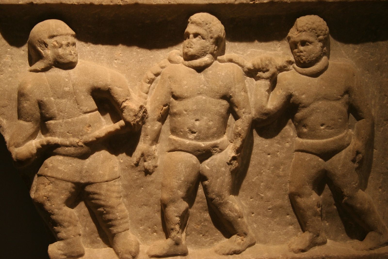 Płaskorzeźba przedstawiająca mężczyznę prowadzącego na łańcuchu przyczepionym do ich szyj dwóch niewolników.