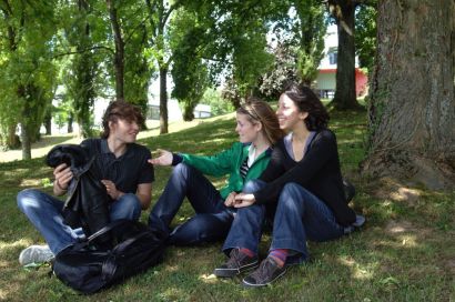 Des étudiants discutent sous un arbre sur le campus de la Bouloie