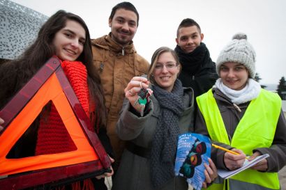 Les étudiants organisateurs posent avec un triangle de signalisation, des clés de voiture et un gilet jaune fluo