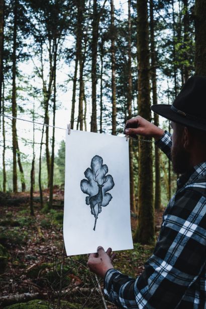 Kiven B affichant en forêt une de ses créations graphiques