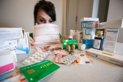 Une jeune femme qui se cache derrière des médicaments et des feuilles de soins