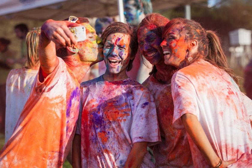 Quatre étudiants recouverts de farine colorée en train de faire un selfie.
