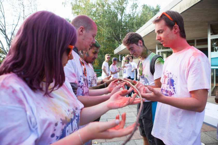 Des étudiants couverts de poudre tiennent une branche en participant à un jeu.