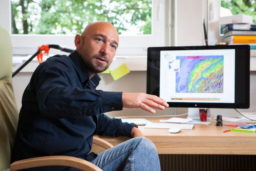 Portrait de Christian Sue devant son écran d'ordinateur avec une carte du Jura.