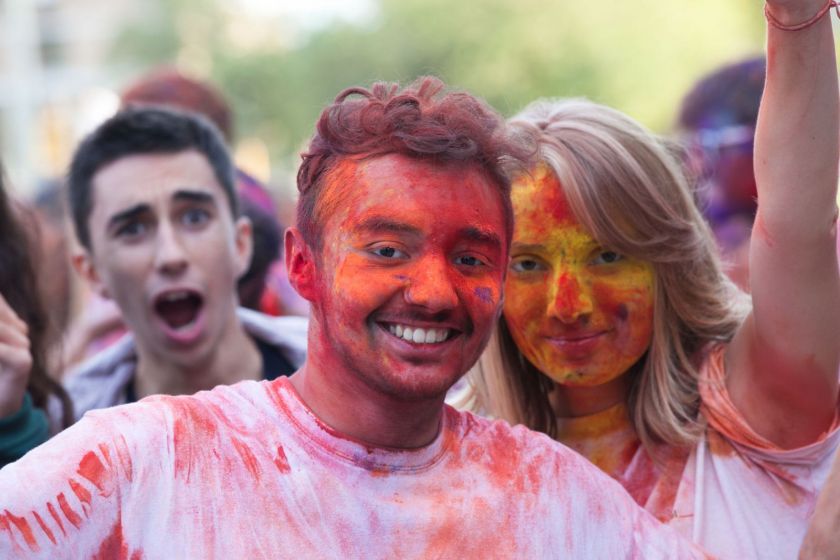 Un jeune homme et une jeune fille souriants et recouverts de poudre colorée.