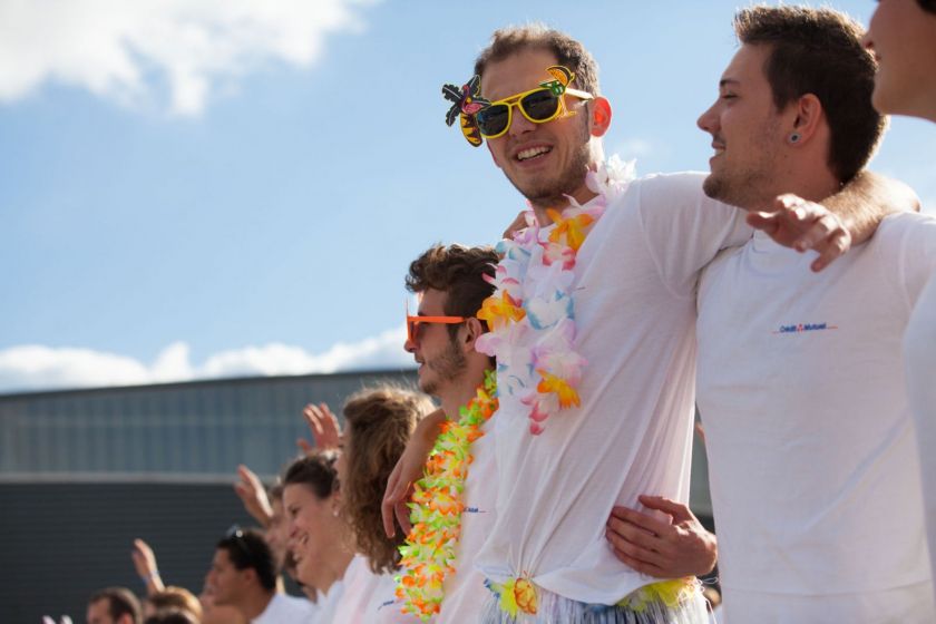 Des étudiants en tee-shirt blanc avec des guirlandes de fleur et des lunettes de soleil décorées sous le soleil.