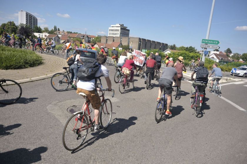 Un groupe de nombreux cyclistes traversant un rond point.