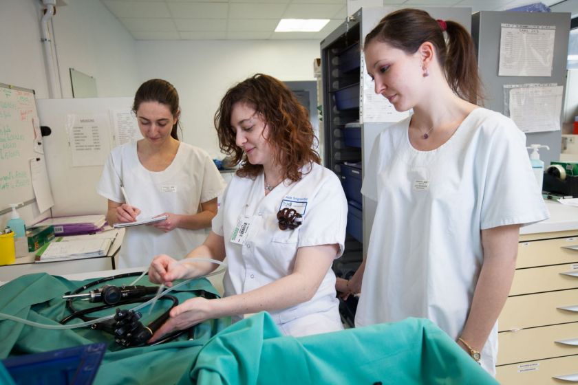 Trois jeunes femmes en blouse blanche à la laverie du service d'endoscopie digestive.