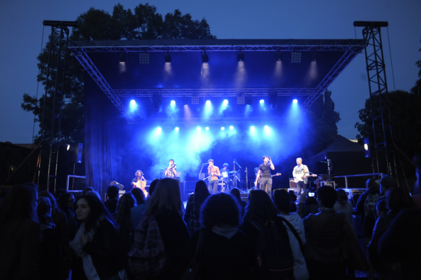 Une scène de concert en extérieur, de nuit, avec des éclairages bleus