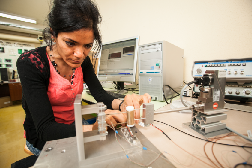 Une jeune femme manipule un banc de caractérisation de microstructures.