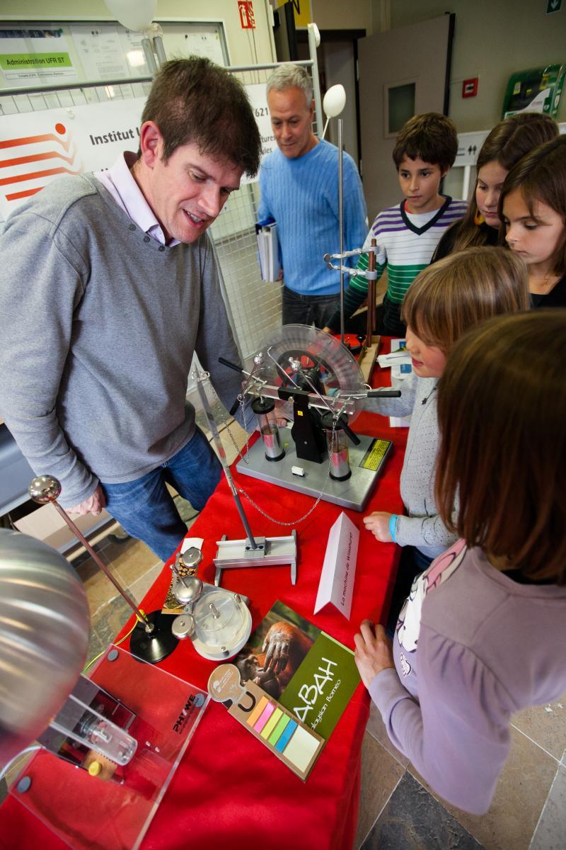 un chercheur montre à plusieurs enfants une expérience sur l'électromagnétisme