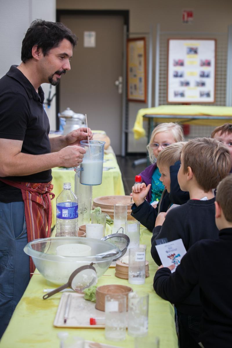 Un homme tient une cruche de lait devant un groupe d'enfants.