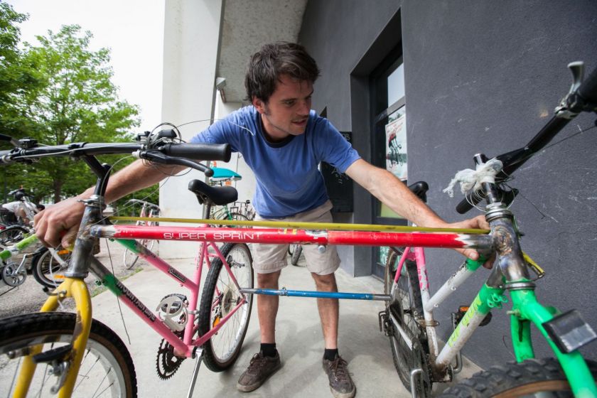 Un jeune homme examine deux vélos montés "en parallèle"