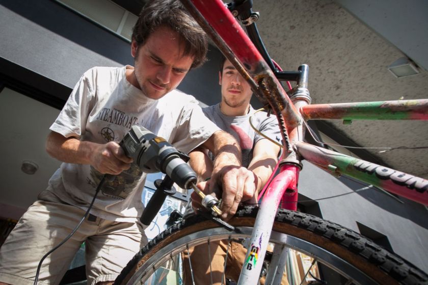 Un jeune homme en train de visser quelqu chose sur un vélo avec une perceuse.