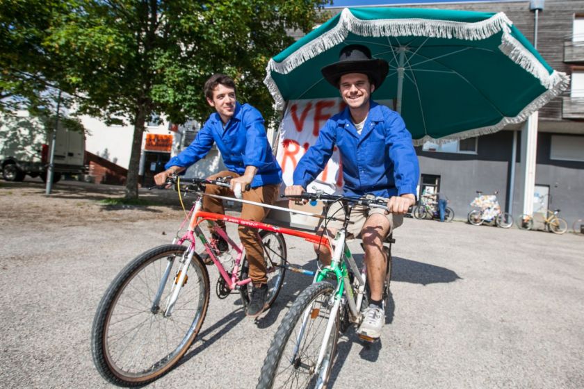 Deux jeunes hommes sur un tanem spécial équipé d'un parasol.