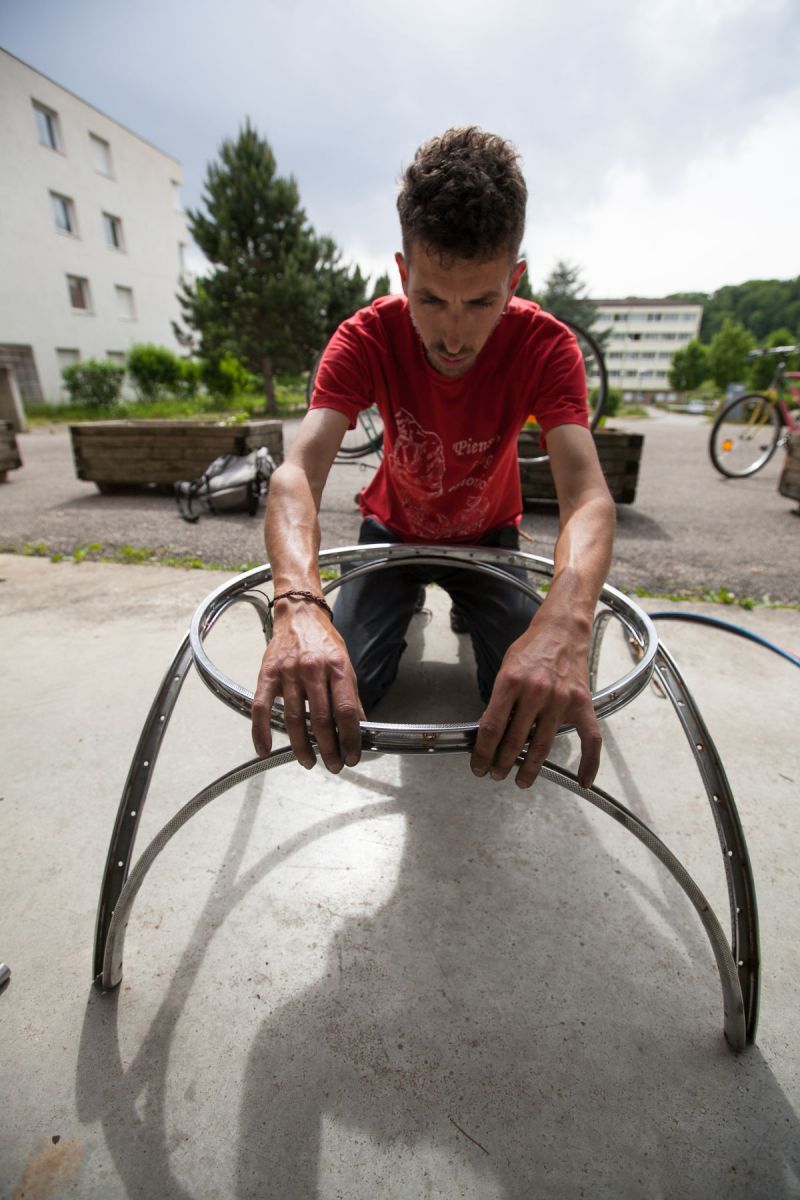 Un jeune homme en train de fabriquer une armature à partir de roues de vélo.