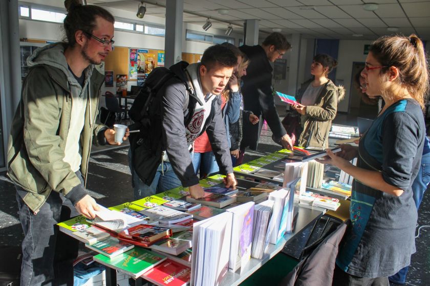 Des étudiants à un stand d'ouvrages sur les langues étrangères