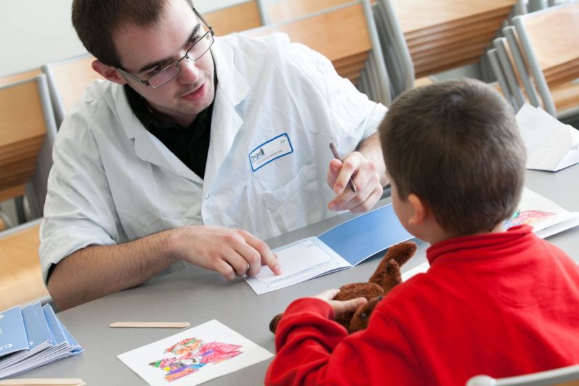 Un étudiant en médecine, crayon en main, interroge un petit garçon.