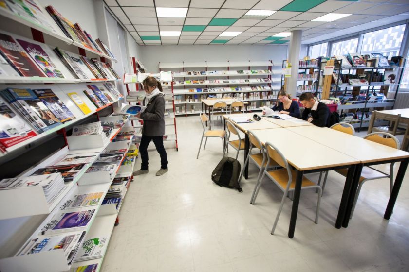 Trois étudiants dans une bibliothèque.