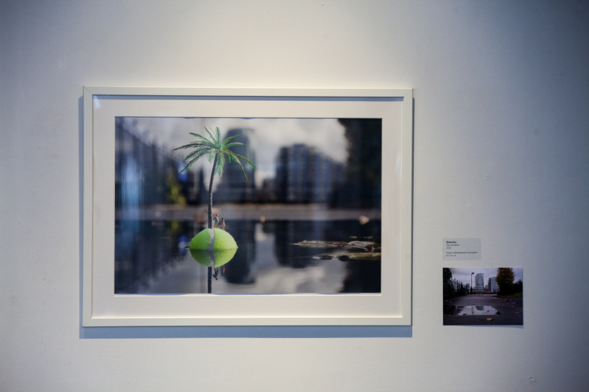 Deux photos de l'artiste Slinkachu exposées sur un mur. On y voit une fausse île faite d'une balle de tennis avec un palmier et des personnages miniatures.