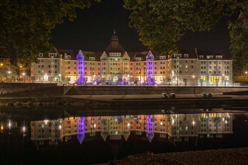 La cité universitaire Canot, vue de l'autre rive, éclairée, avec son reflet dans l'eau.