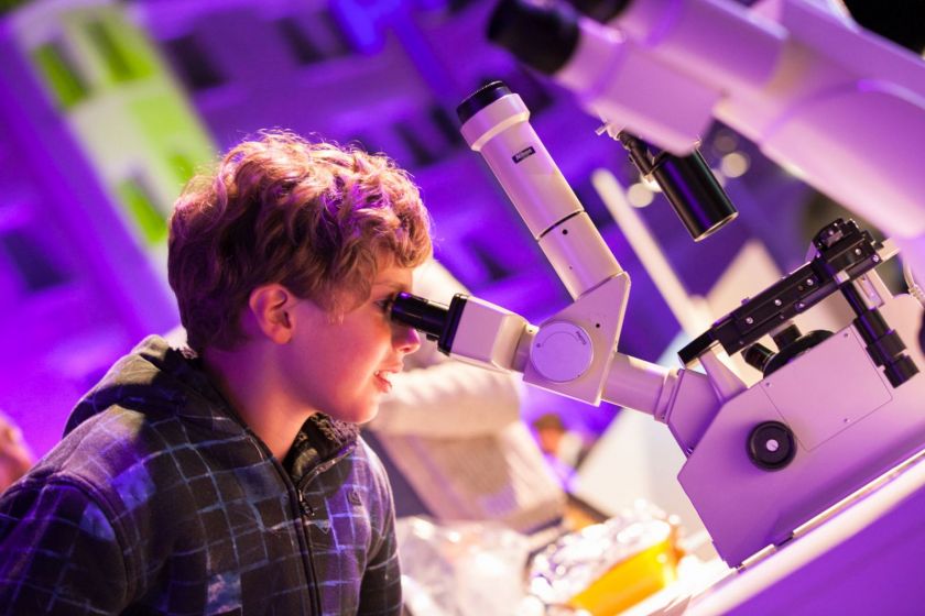 Un jeune garçon regarde dans un microscope.