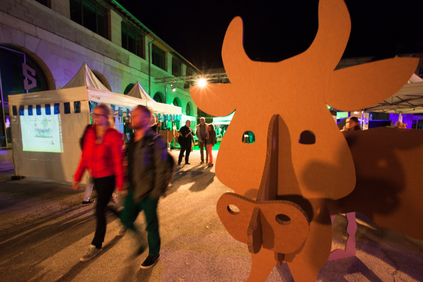 Une vache en carton, des visiteurs qui passent.