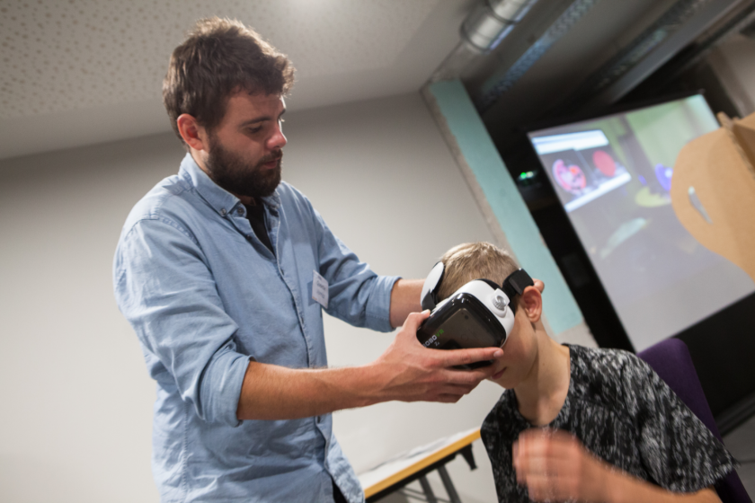 Un jeune homme place un casque de réalité virtuelle sur la tête d'un jeune garçon.