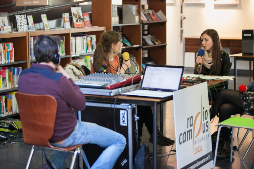 Un plateau radio avec trois personnes installé dans une bibliothèque