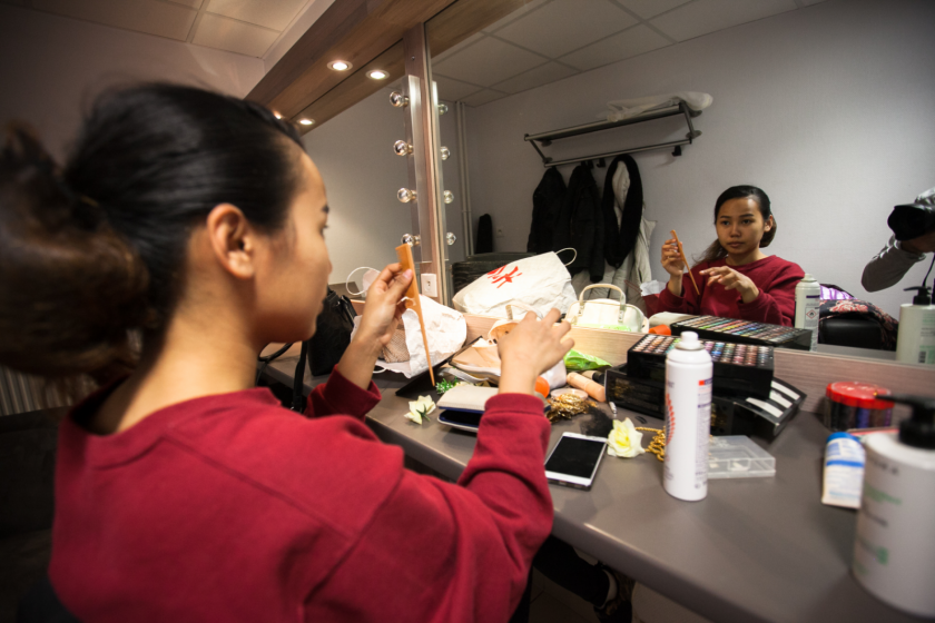 Une jeune fille devant un miroir dans les loges.