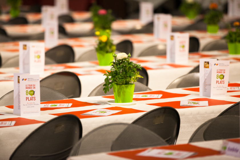 Des rangées de tables décorées avec des fleurs et le menu du tour du monde en 80 plats.