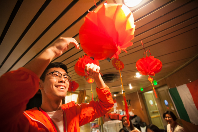 Un jeune chinois installe au plafond des boules de papier colorées.