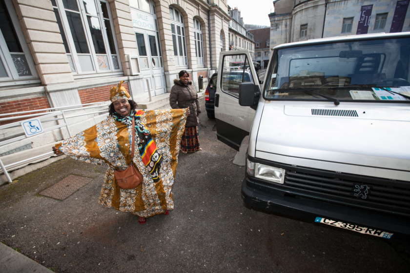 Une dame sénégalaise souriante en boubou sort d'un camion.