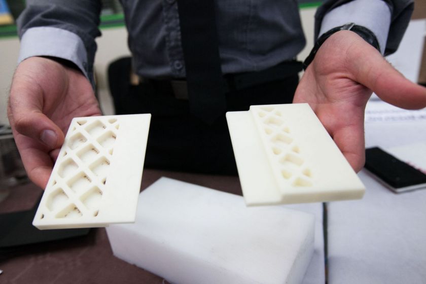 Deux mains montrent des pièces mécaniques faites à l'imprimante 3D.