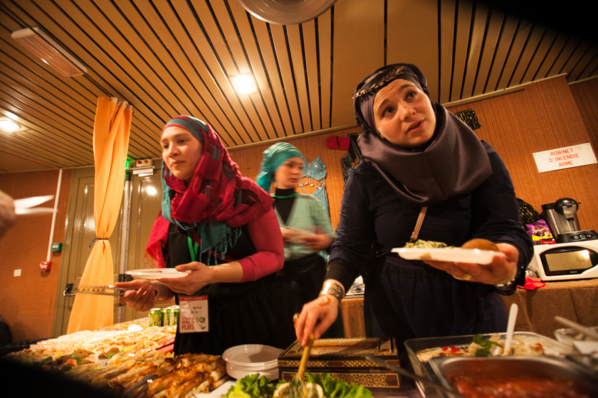 Trois femmes portant le vioile devant un stand en train de servir de la nourriture aux visiteurs?