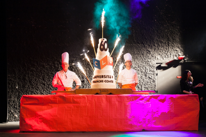 Un gateau à étages avec deux chefs cuisiniers en toque de chaque côté.