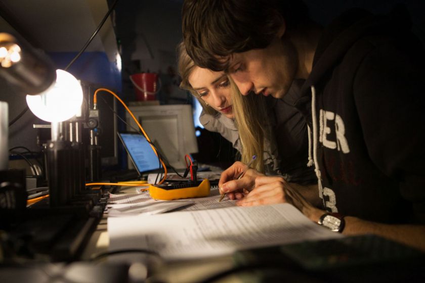 Un étudiant et une étudiante penchés sur un même document.