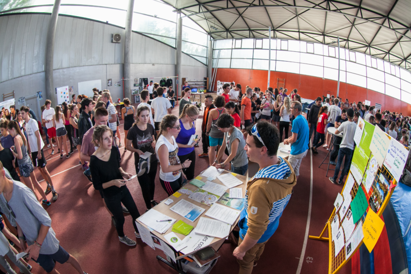 Vue intérieure de la grande halle de l'U-sports remplie d'étudiants et de stands.