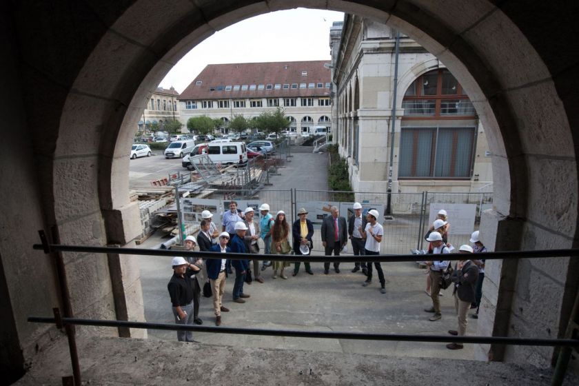 A travers une arcade on voit les gens qui participent à la visite de chantier.