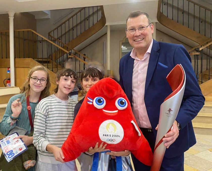 3 collégiennes aux côtés de Eric Monnin avec la flamme olympique et une phryge des JO de Paris