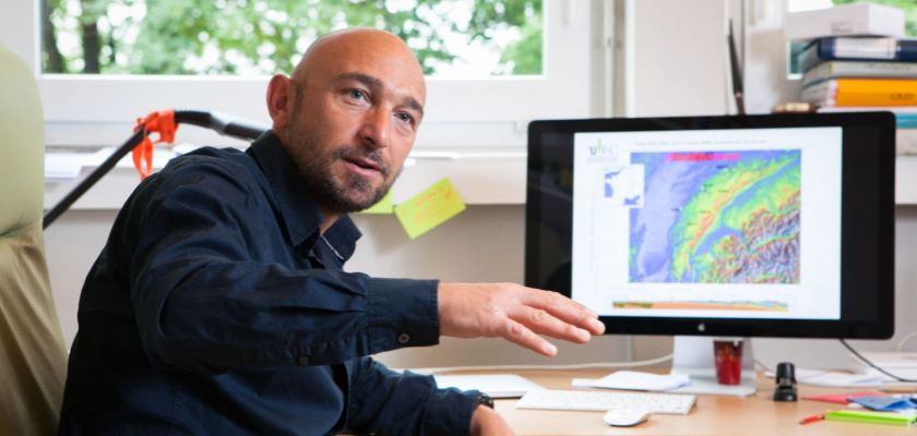 Portrait de Christian Sue devant son écran d'ordinateur avec une carte du Jura.