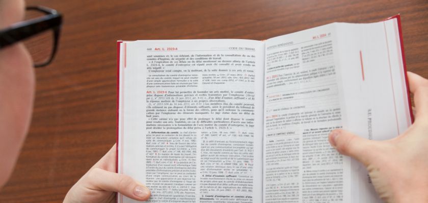 une jeune femme de dos lisant un livre de droit