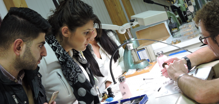 Dansun atelier, un homme montre les détails d'une montre à trois étudiants.