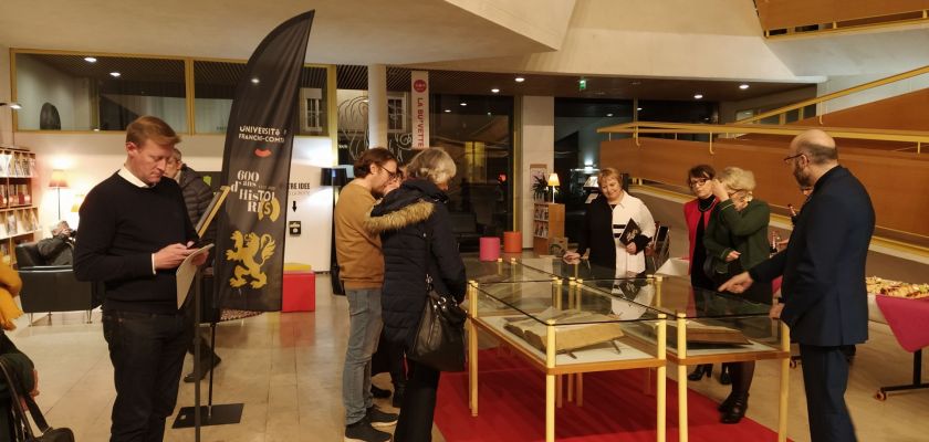 publics entourant des vitrines de documents anciens exposés à la BU Belfort dans le cadre des 600 ans de l'université