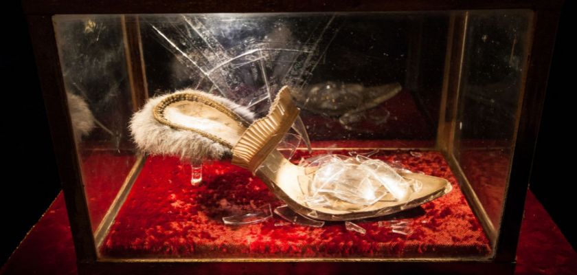 Chaussure en verre brisé dans une vitrine sur un coussin de velours rouge.