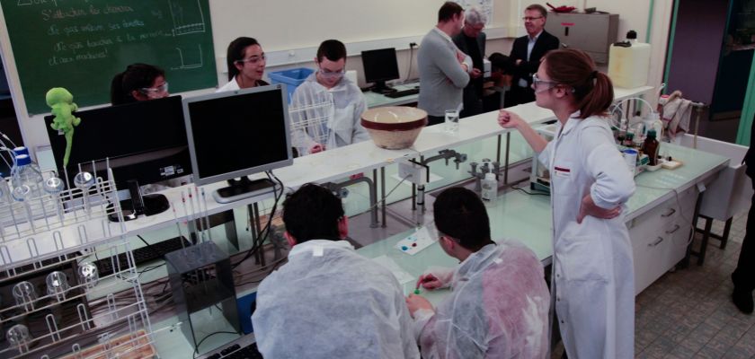 Des collégiens en blouse dans une salle de TP de Chimie