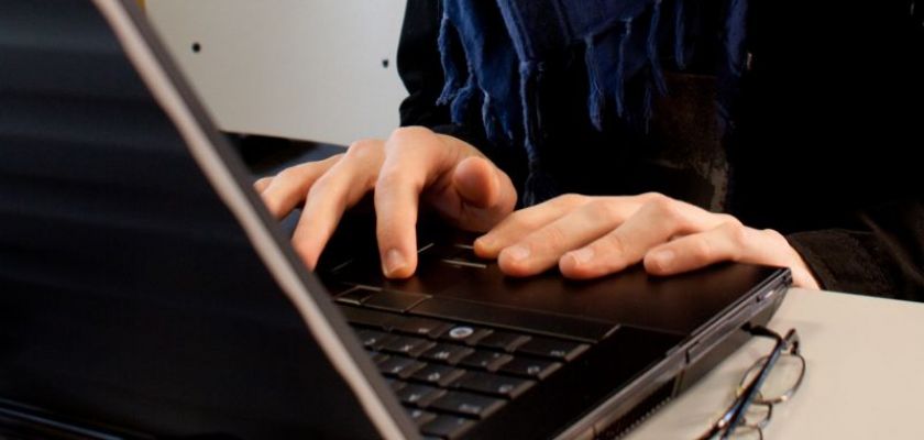 Un jeune homme devant un clavier d'ordinateur.