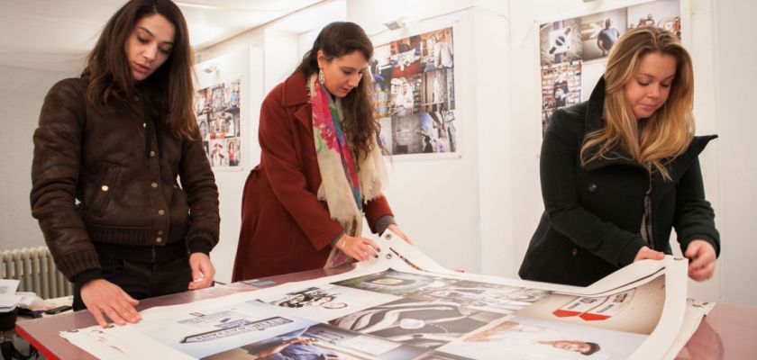 Trois étudiantes de la licence professionnelle METI en train d'examiner des grands tirages photos lors de l'accrochage.