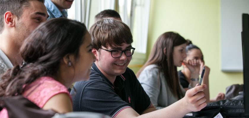 Un groupe d'étudiants travaillent ensemble en riant.