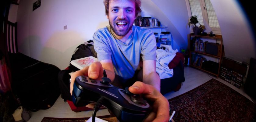 Un homme tient une manette de jeux vidéos.